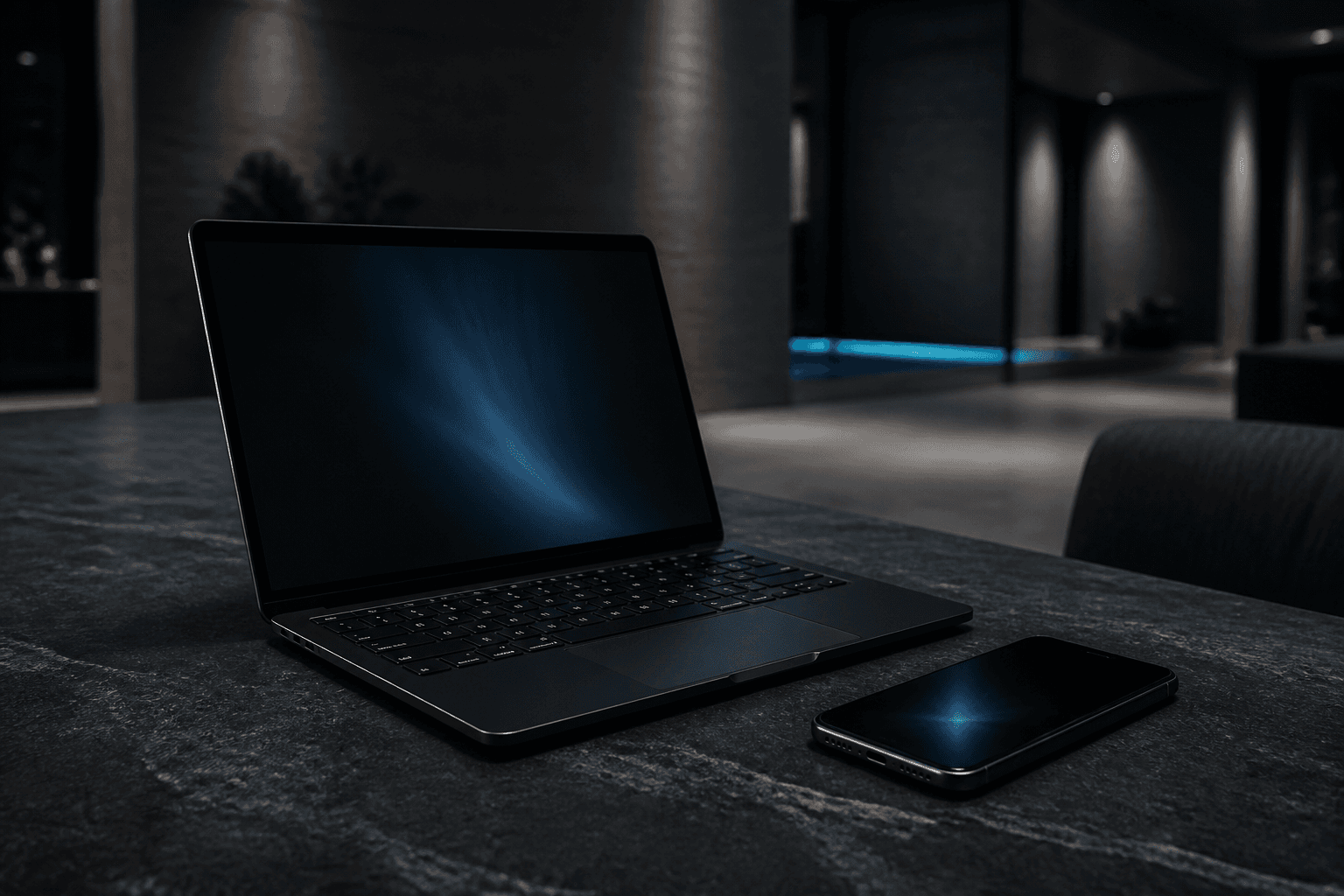 Laptop and phone on a slate surface in a dark interior
